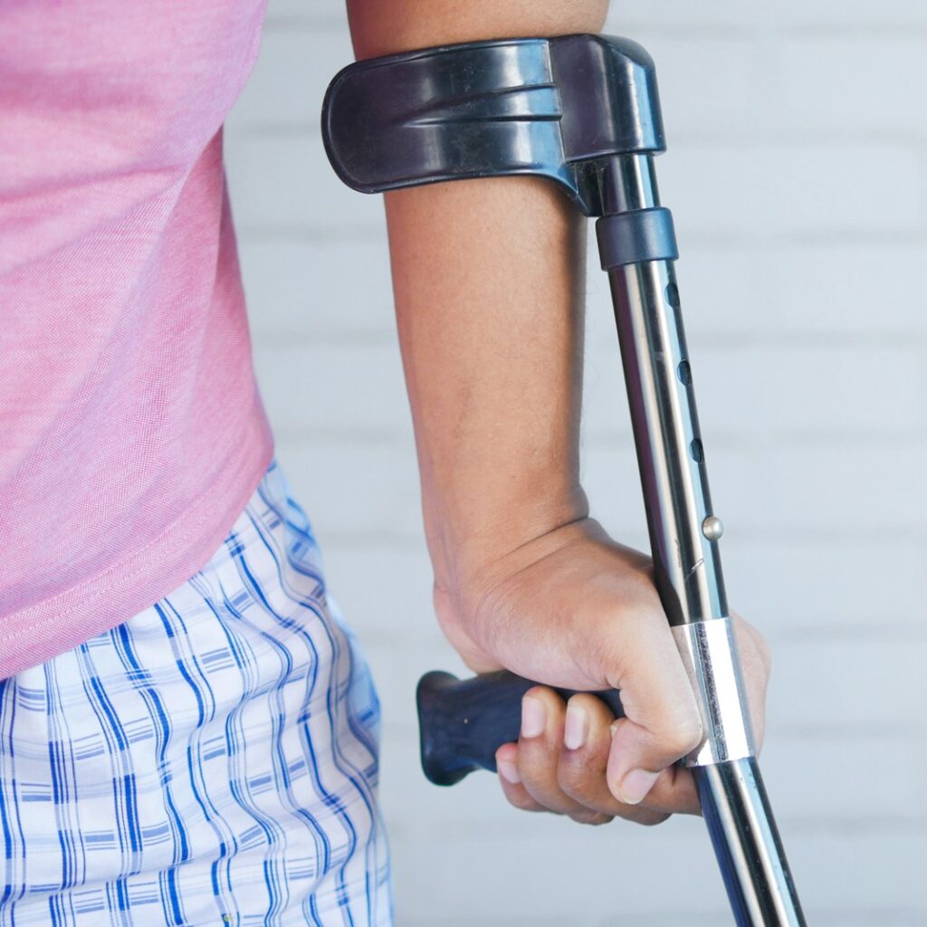 a person holding a crutch and walking cane